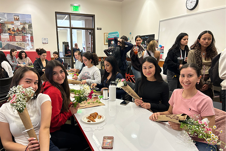 students holding flowers and sitting around a table